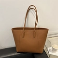 Brown litchi grain leather tote bag with long straps on a black sofa background - Brown