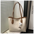 Dettaglio della borsa tote bicolore panna e marrone con ciondolo mostro peloso - Con Ciondolo / Bianco