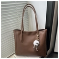 Dettaglio della borsa tote marrone in pelle PU con ciondolo in peluche e ombre soffuse - Con Ciondolo / Marrone