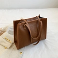 Close-up of caramel tote bag featuring embossed graffiti texture on soft white bedding - Brown