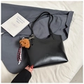 Detail of black leather tote bag with plush bear charm and ribbon on soft fabric - With Ornament / Black