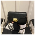 Detail of black crocodile pattern bag featuring a gold rectangular clasp and chain strap - Black