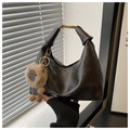 Close-up of black crescent hobo bag with gold hardware and a cute plush animal charm - Black With Pendant