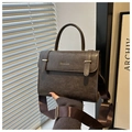 Primer plano del bolso bandolera retro marrón con correa ancha y herrajes dorados - café