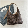 Detail van luipaardprint tote bag met bruine riemen en een denim jack gestyled - Bruin