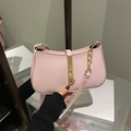 Pink minimalist underarm bag with gold metal lock and dual shoulder straps on a book - Pink