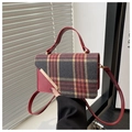 Detail of red leather handle and gold metal trim on a vintage plaid crossbody bag - Red