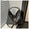 Macro view of matte black retro leather tote with decorative gold buckle and strap details - Black