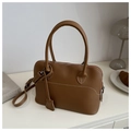 Dettaglio borsa Boston in pelle marrone con cuciture bianche e tasca su tavolo bianco - Marrone