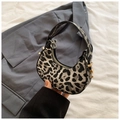 Detail view of mini leopard print crescent bag with golden buckle on grey blazer backdrop - Black