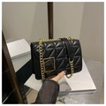 Nahaufnahme einer schwarzen Stepptasche mit goldenem geometrischem Drehverschluss - Schwarz