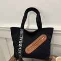 Large black canvas tote bag with brown leather patch and white lettered strap detail - Black