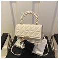 Detalle de bolso acolchado beige con asa plisada elegante y cierre metálico en tono dorado - Blanco