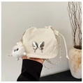 Detalle del bolso saco plisado blanco con mariposa plateada y llavero de peluche suave - Blanco
