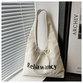 Detail of canvas tote bag with Rebawaycy lettering and decorative ribbon bow - White