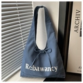 Blue canvas tote bag detail with Rebawancy text and decorative ribbon bow in natural light - Blue