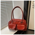 Detail view of deep red patent leather handbag featuring dual front flap pockets and glossy finish - Red