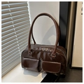 Detail of glossy brown handbag featuring double flap pockets and silver metal hardware - Brown
