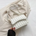 Sac bandoulière blanc plissé chic avec boucle dorée posé sur un blazer beige - Blanc