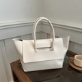 Borsa a mano minimalista bianca in pelle capiente posata su un tavolino moderno - Bianco