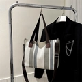 Bolso tote de lona a rayas con correa ajustable colgado en un perchero de metal - Gris