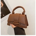 Detail shot of a brown lychee-textured handbag with top handle and metal bar closure - Brown