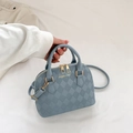 Blaue Muschelhandtasche mit Rautenmuster und Goldbeschlägen, handgehalten präsentiert - Blau