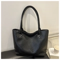 Detalle de la textura trenzada y costuras reforzadas del asa en un bolso tote negro - Negro
