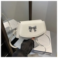 Detail of white mini crossbody bag featuring a 3D silver metal bow buckle and PU strap - White