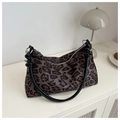 Detail der Vintage-Tasche mit Leopardenmuster und schwarzen Griffen im minimalistischen Regal - Schwarz