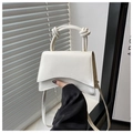 Detail view of a white mini bag with wavy flap design and knotted handle style - White