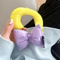 Detail of vibrant yellow and purple oversized bow phone grip with glossy texture - Yellow + Purple Contrast