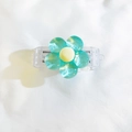 Close-up of cyan 3D resin flower phone clip with transparent base and yellow center - Back Clip Only / Blue