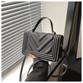 Detail of the black quilted crossbody bag with chevron pattern and gold metal hardware - Black