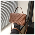 Detailed close-up of caramel brown handbag featuring unique V-quilted faux leather texture - Brown