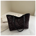 Detalle del bolso tote de leopardo con asas de cuero negro y remaches dorados - café