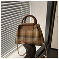 Detail of vintage plaid handbag featuring round resin handles and a slim crossbody strap - Brown