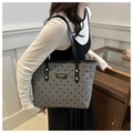 Close-up of gray canvas tote bag featuring black polka dots and leather logo tag - Black Polka Dot