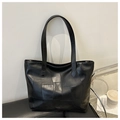 Dettaglio di una borsa tote in pelle nera con design patchwork geometrico e manici - Nero