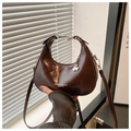 Detail of brown crescent bag with silver clover pendant and white fashion text - Coffee