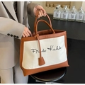 Retro canvas tote bag with Frida Kahlo print and brown leather trim in a handheld view - Off White