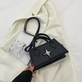 Minimalist black square handbag with silver star detail and crossbody strap on white suit - Black