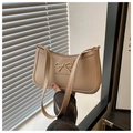 Detalle del bolso bajo el brazo beige en cuero con hebilla de lazo dorado y costuras finas - Caqui