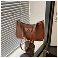 Detalle de bolso de hombro en cuero marrón oscuro con hebilla decorativa de lazo dorado - Marrón