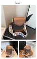 Vista dettagliata delle cuciture in pelle marrone e della scritta moda sulla borsa a tracolla - caffè