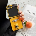 Detail of yellow leather Z Flip case with 3D bear ornament and crochet orange pendant - Cross Texture Smiley Bear Persimmon Pendant Orange