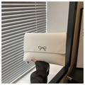 Close-up of a white envelope clutch bag featuring a silver metal bow clasp and smooth texture - White
