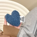 Close-up of heart-shaped blue plush phone grip with 'NEVER GIVE UP!' woven label detail - Blue