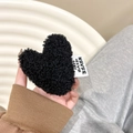 Detail of plush black heart phone grip with lamb wool texture and 'Never Give Up' label - Black