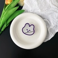 Macro shot of cute purple rabbit phone grip mirror on a white plate with floral decor - Deep purple